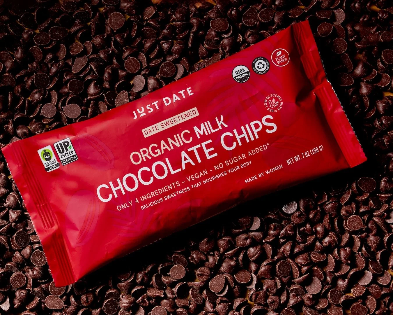 A red package of organic milk chocolate chips on a bed of chocolate chips.