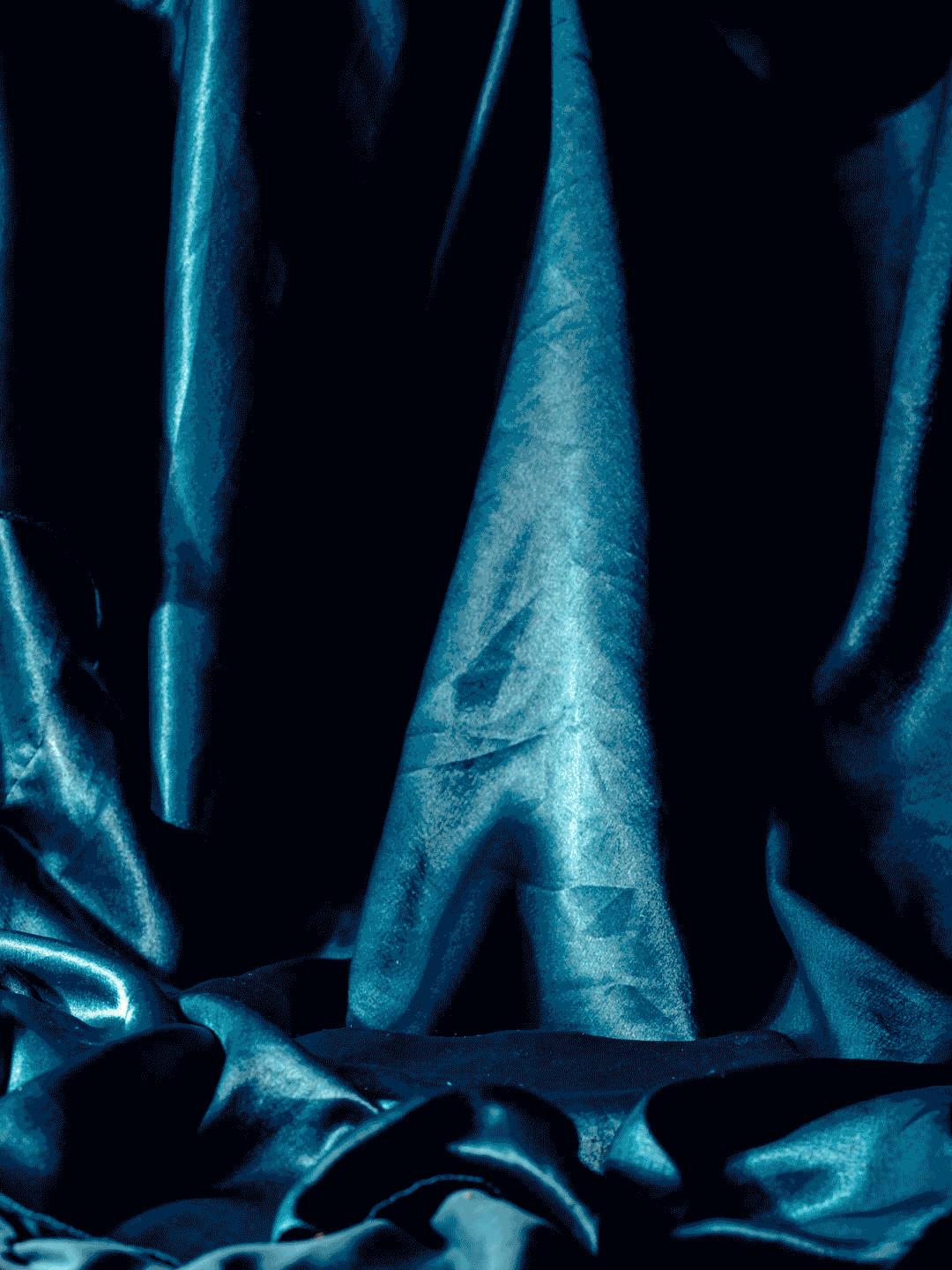 Close-up of dark blue satin or silk fabric with shiny, smooth texture, folded and draped.