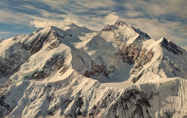 Snow-covered mountain peaks under a cloudy sky.