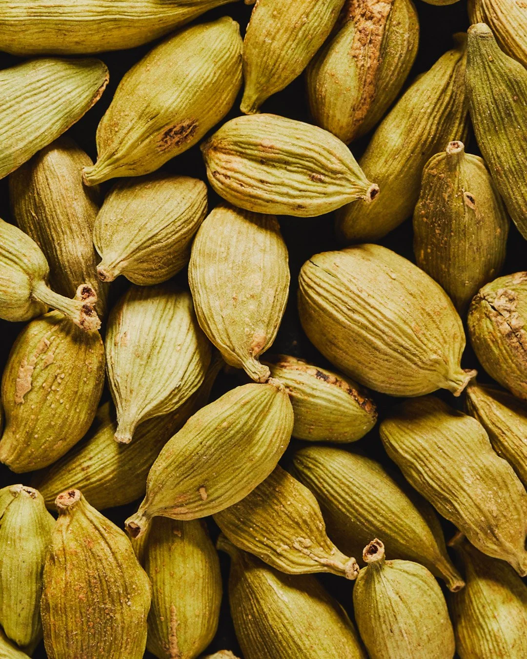 Close-up of green cardamom pods scattered together.
