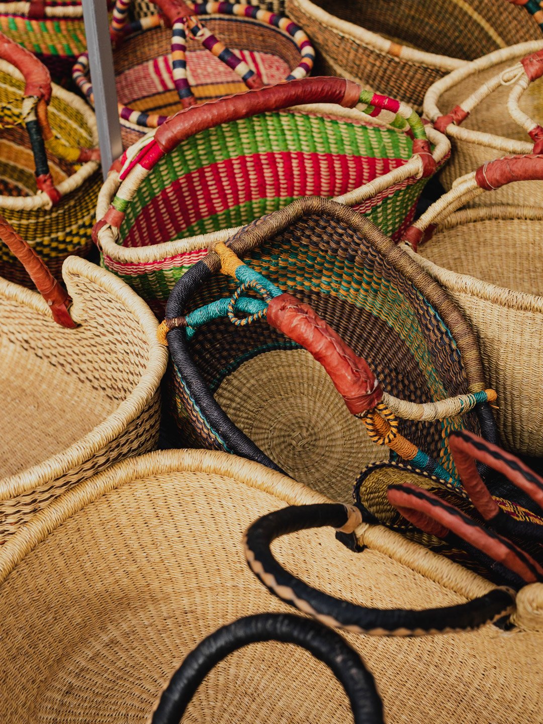 Colorful woven baskets with varied patterns and handles stacked together.