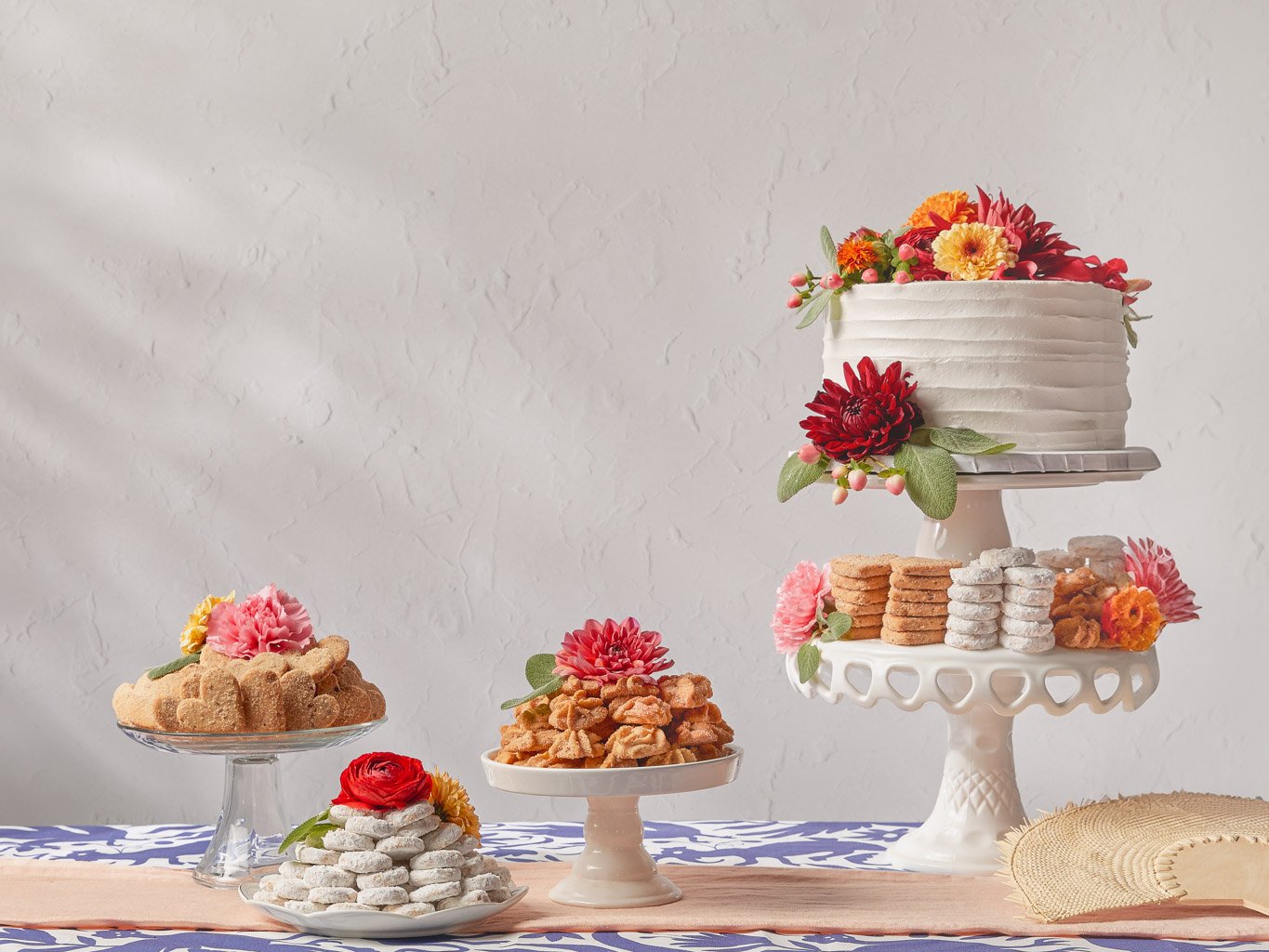 A decorated table with a white cake with flowers, assorted cookies, and candies on display.