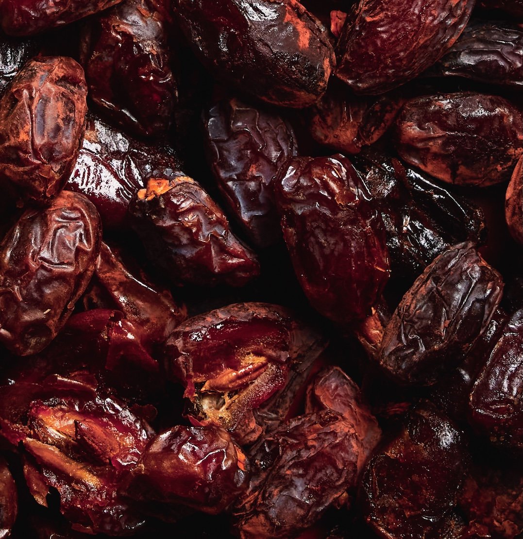 Close-up of a pile of roasted dates with wrinkled, dark brown to black skins.