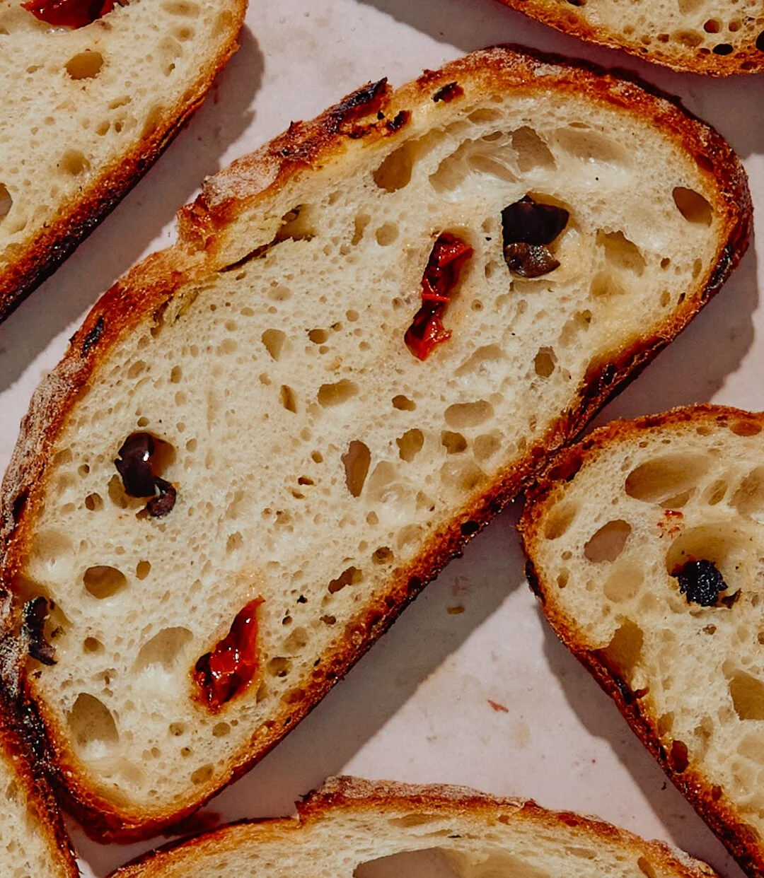 Slices of toasted Italian bread with black and red pepper flakes.