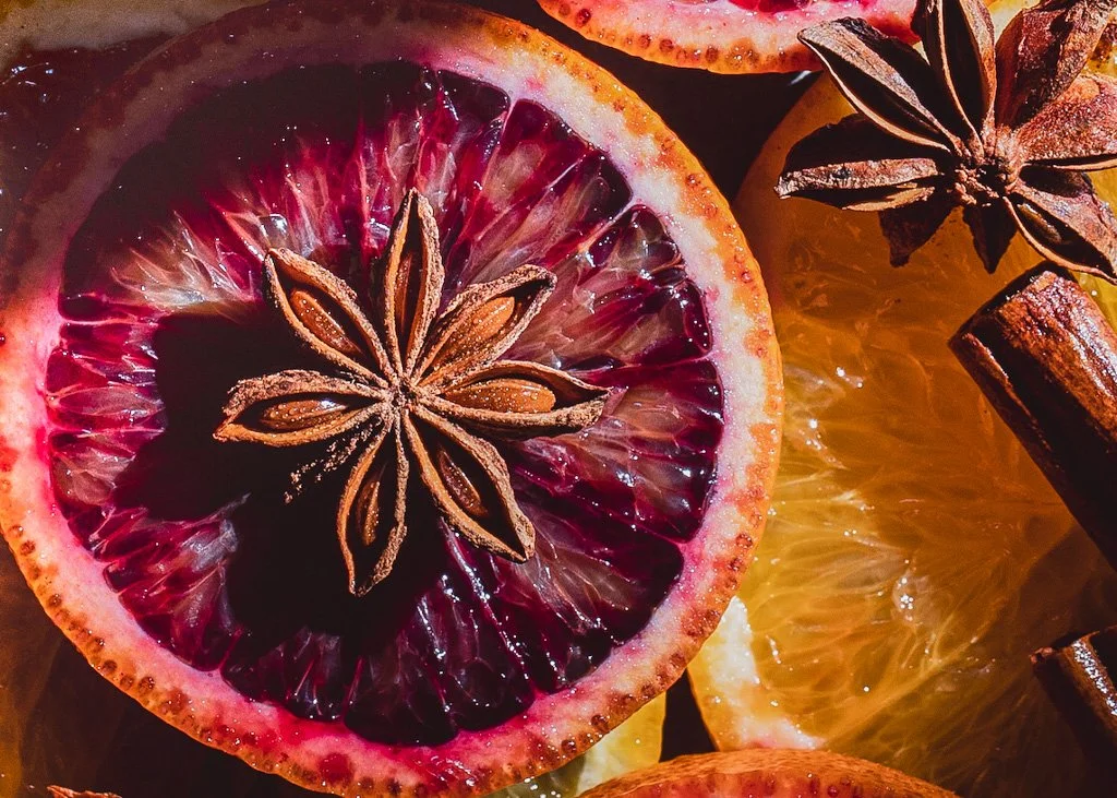 Close-up of sliced blood orange with star anise and cinnamon sticks.