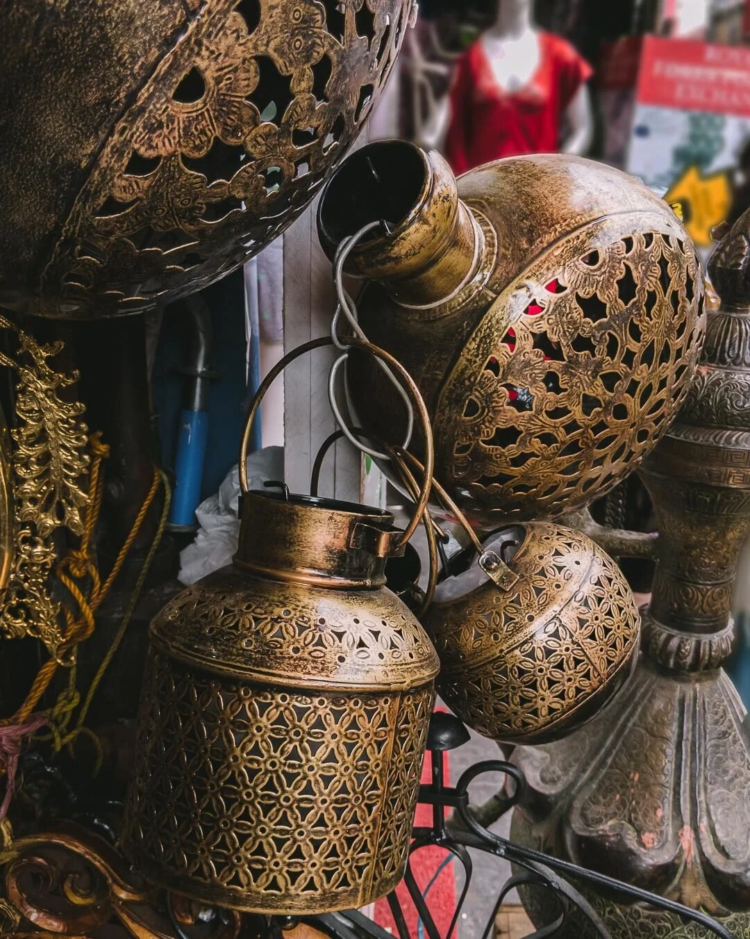 Golden ornamental lanterns with intricate cut-out patterns displayed together at a shop.