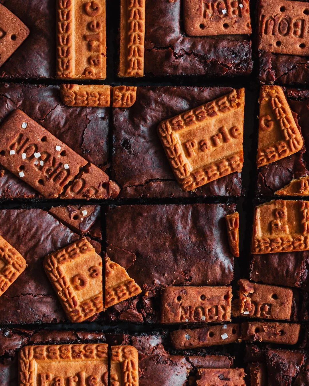Close-up of broken brownie squares topped with vanilla wafers and sugar crystals.
