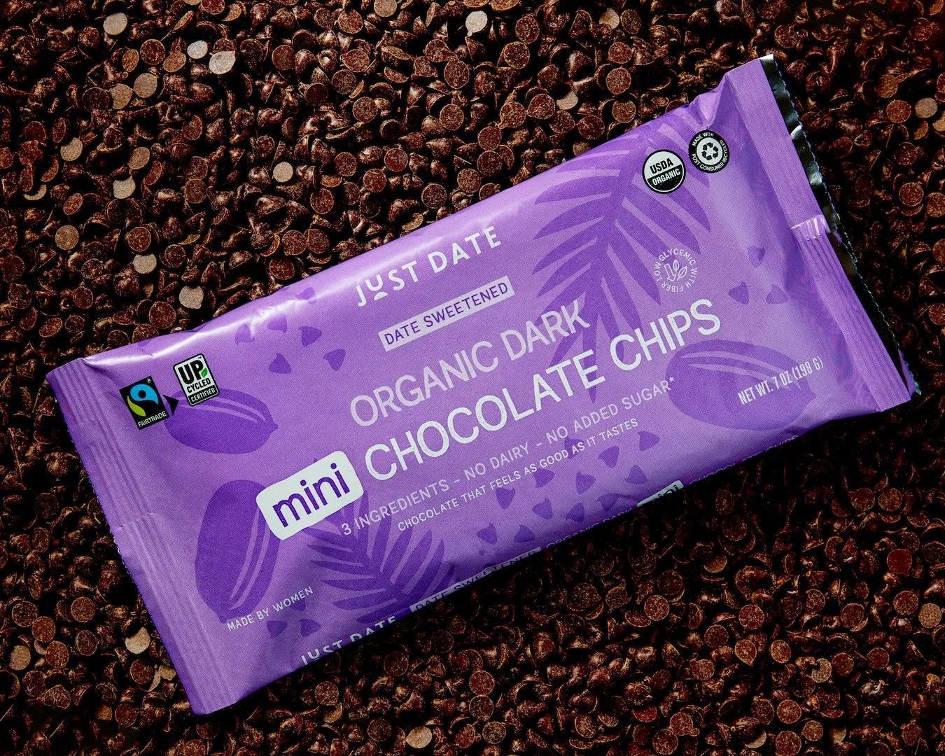 Purple package of mini organic dark chocolate chips resting on a bed of chocolate chips.