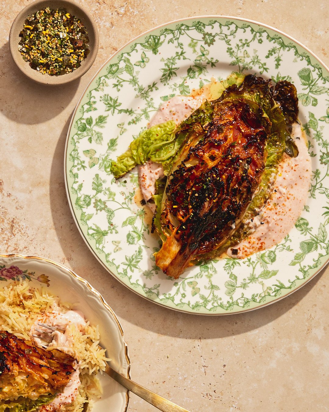 Baked stuffed eggplant with tomato sauce, served with a side of rice and a small bowl of crushed pistachios and spices.