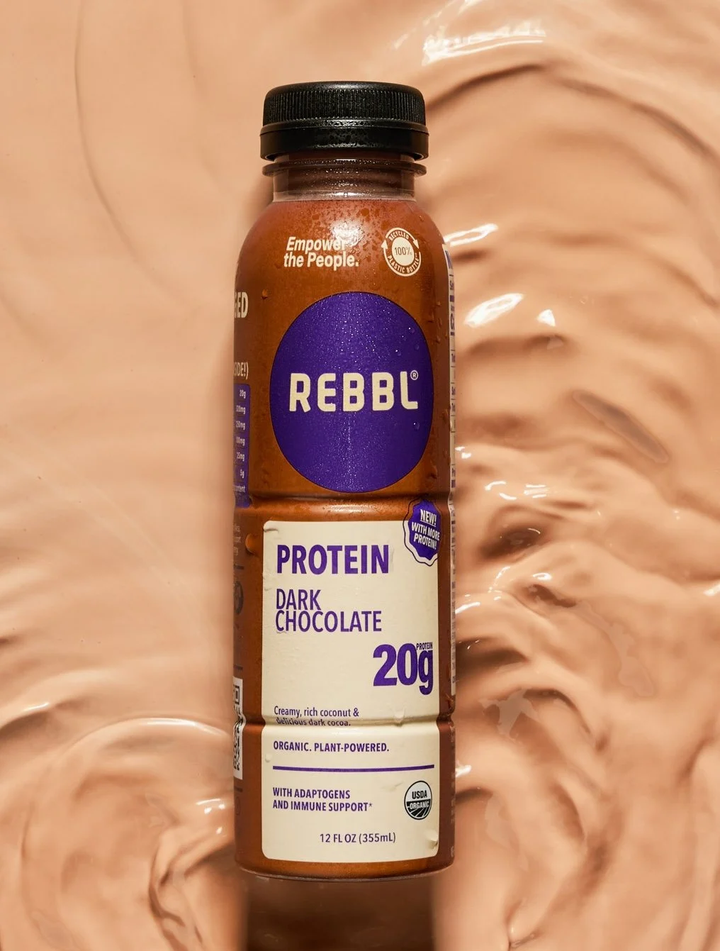 A bottle of REBBL Protein Dark Chocolate drink against a swirling chocolate-colored background.