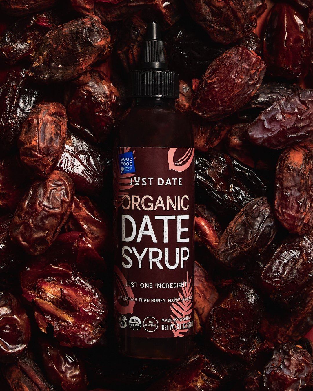 Bottle of organic date syrup surrounded by dried dates.