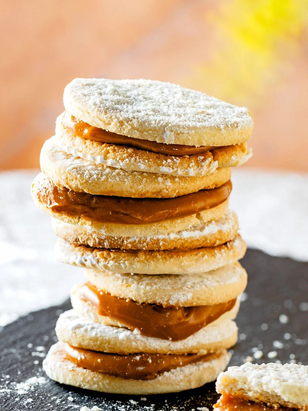 Stack of cookies filled with caramel, some topped with powdered sugar