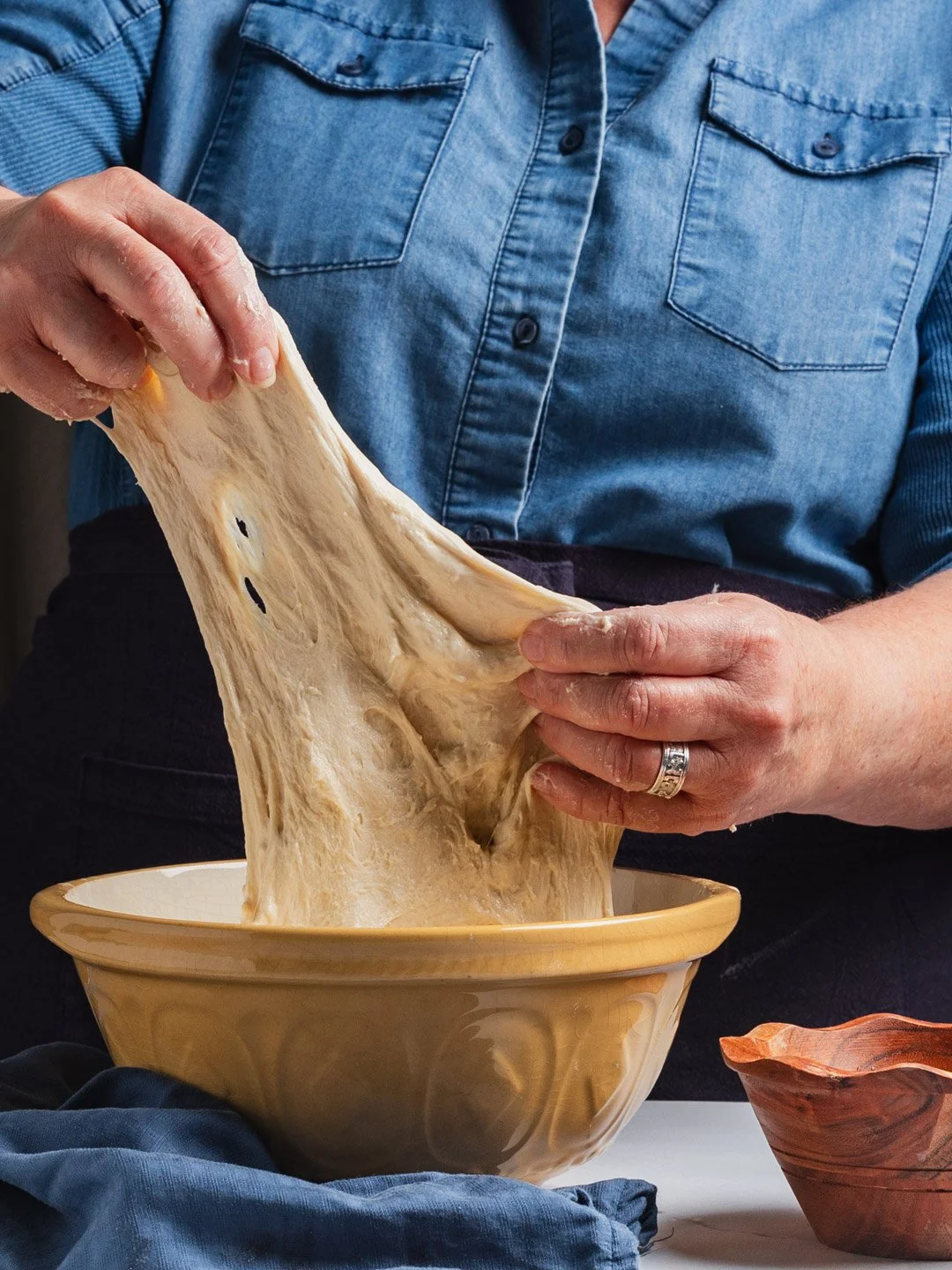 Person stretching melted cheese over a bowl of food.