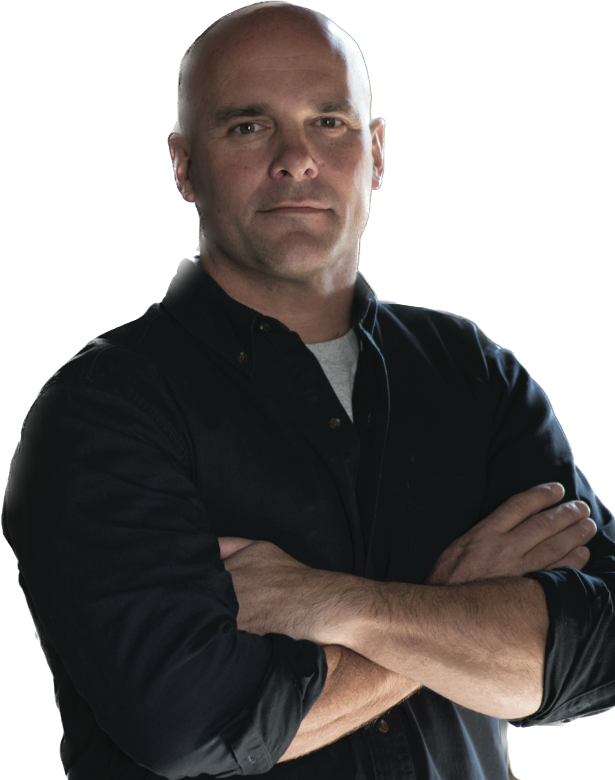 A man with a bald head and light skin, wearing a black button-up shirt with folded arms.