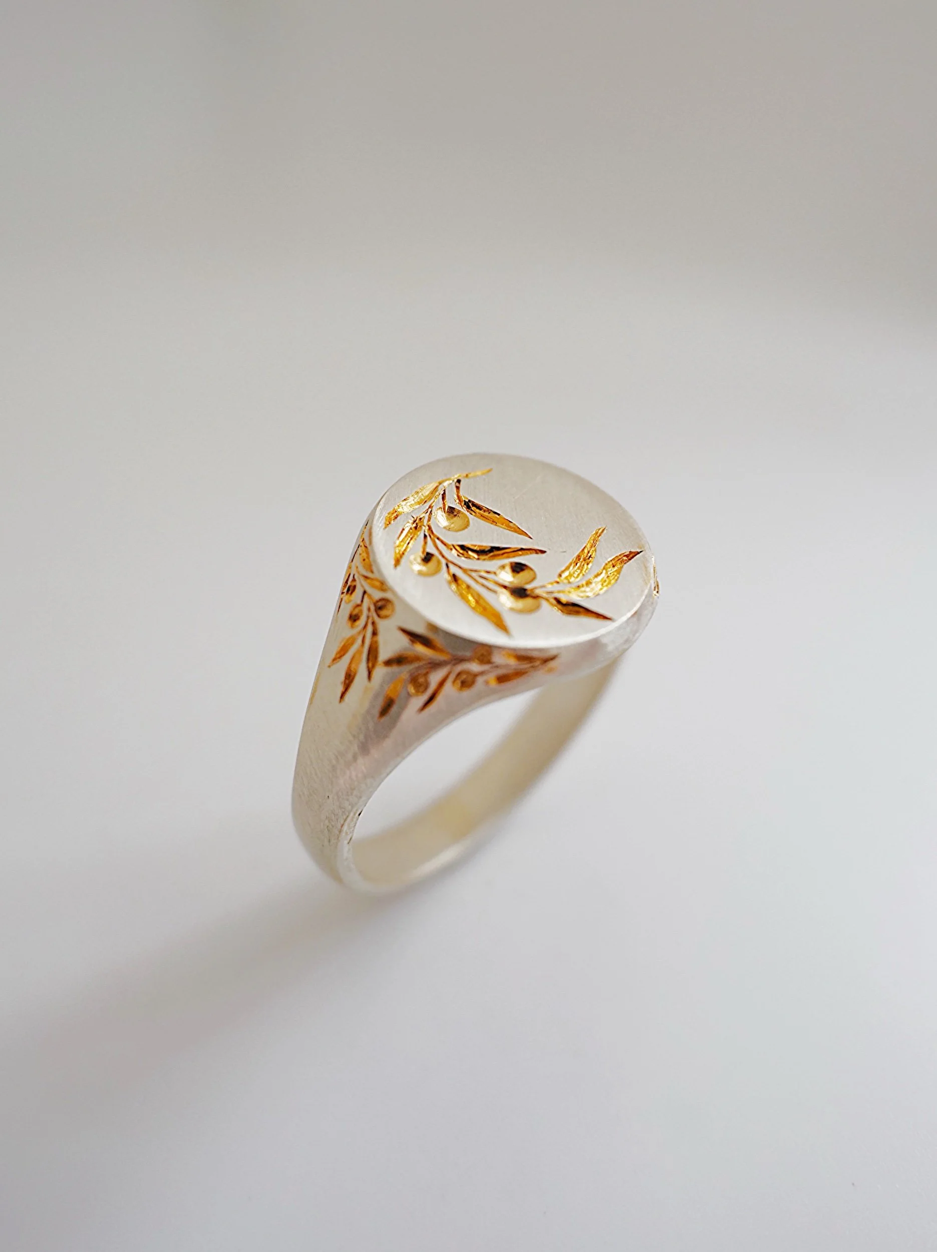 A ring with gold leaf and branch details on a light, plain background.