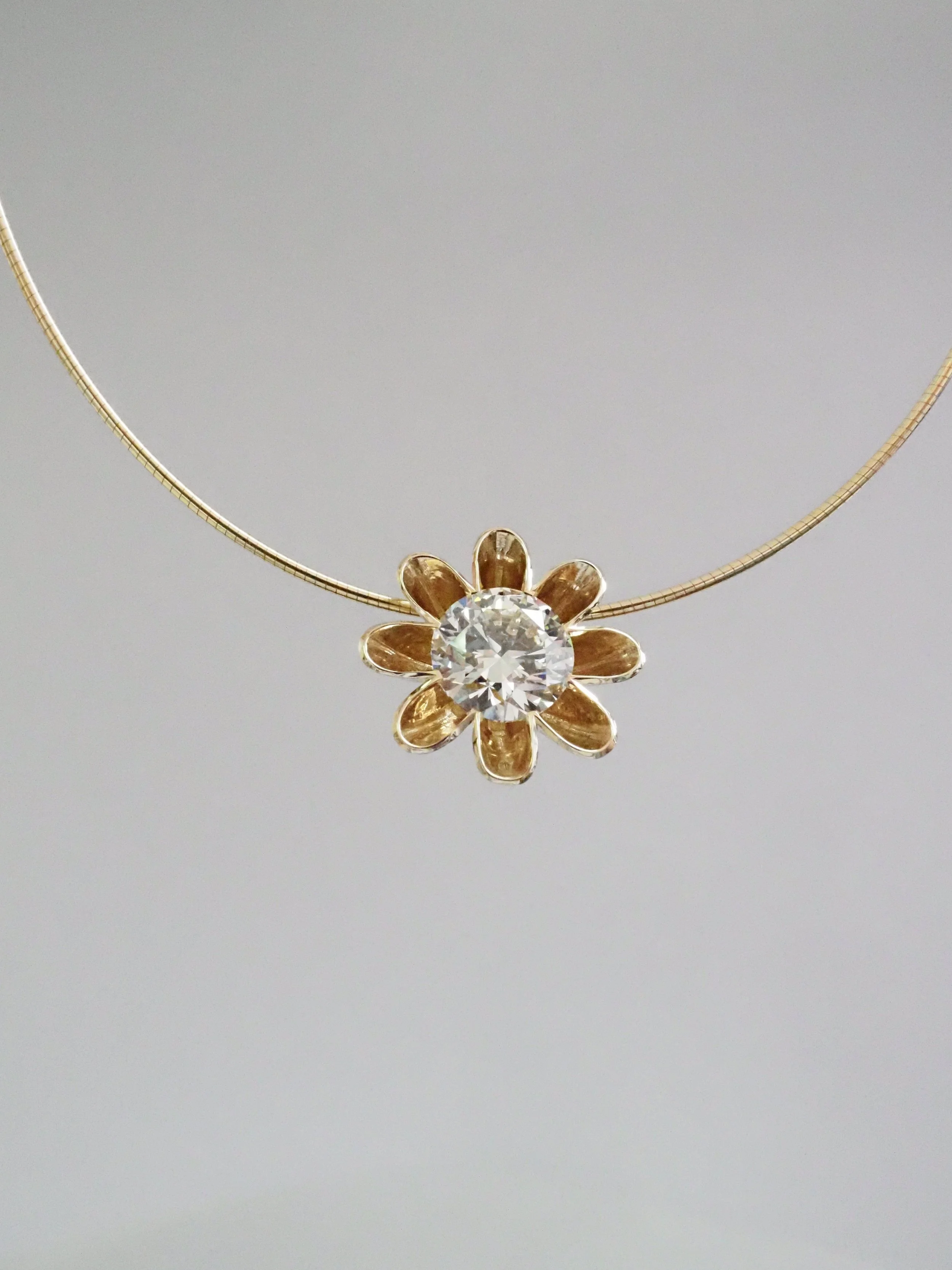 Gold necklace with a sunflower-shaped pendant featuring a large central diamond.