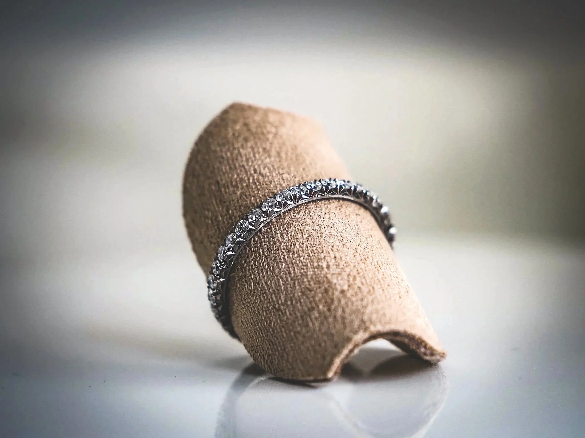 A diamond ring on a beige jewelry display stand.