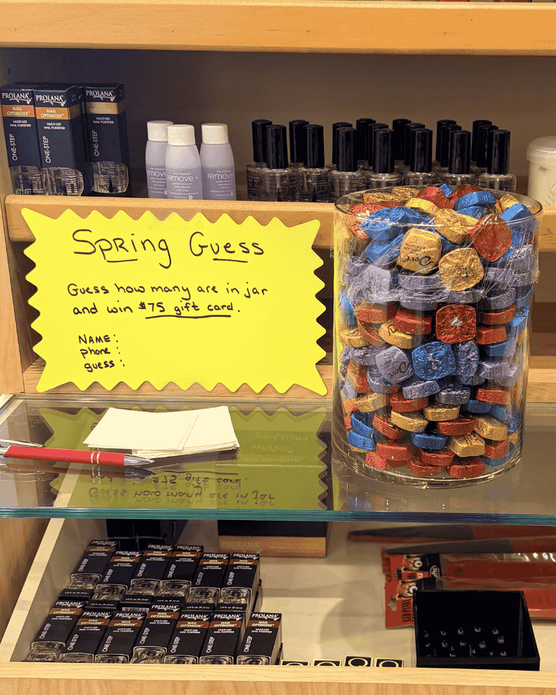 Spring chocolate guessing contest display at Merle Norman studio with jar of chocolates and sign offering chance to win a $75 gift card