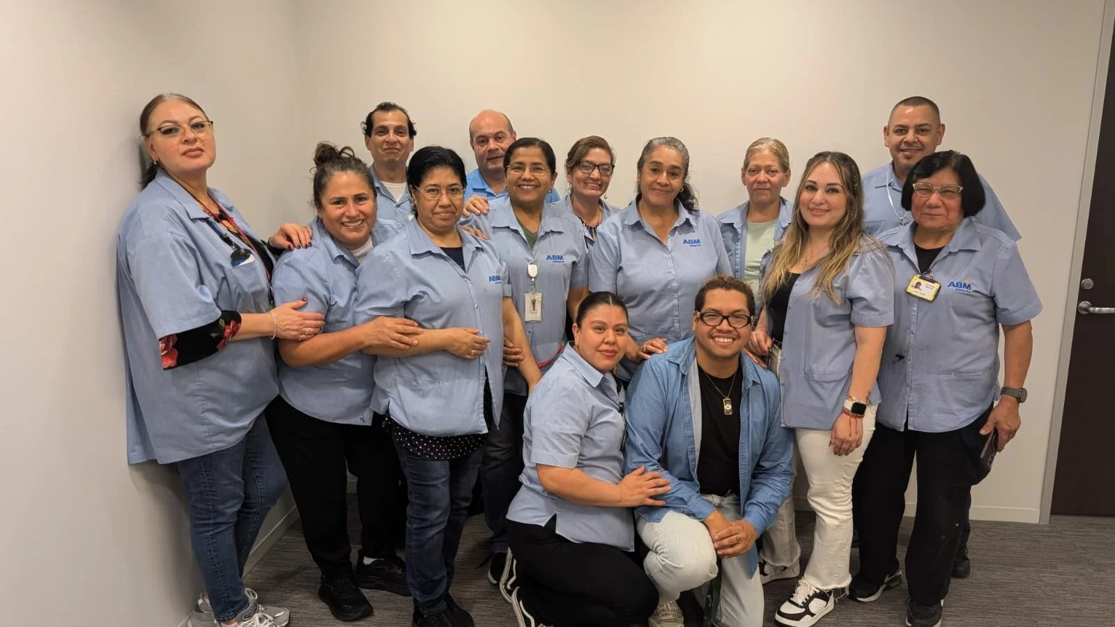 Group of healthcare professionals wearing blue uniforms posing together in an office.