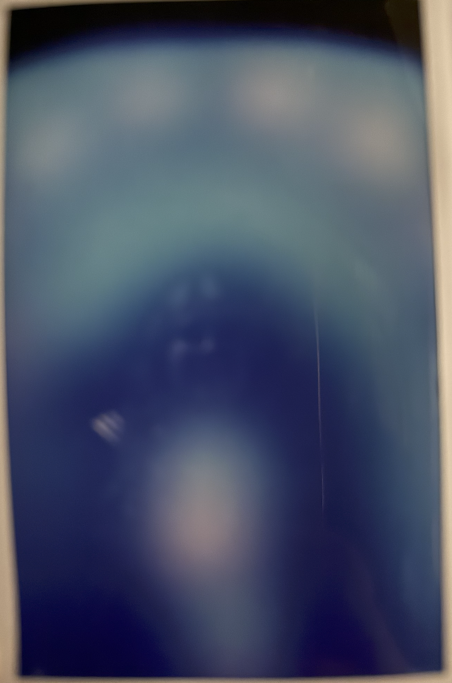 iPhone photo of Lisa's aura photo print. The aura photo has a strong heart-light and the over-arching aura colors are light blue, soft pink, and white.