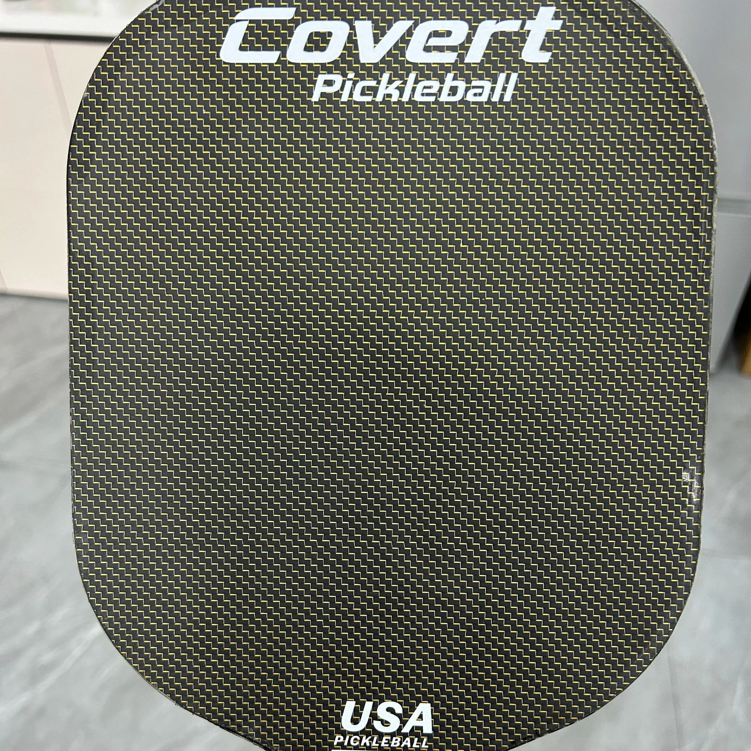 A black and yellow textured pickleball paddle with the words 'Covert Pickleball' at the top and 'USA Pickleball' at the bottom.