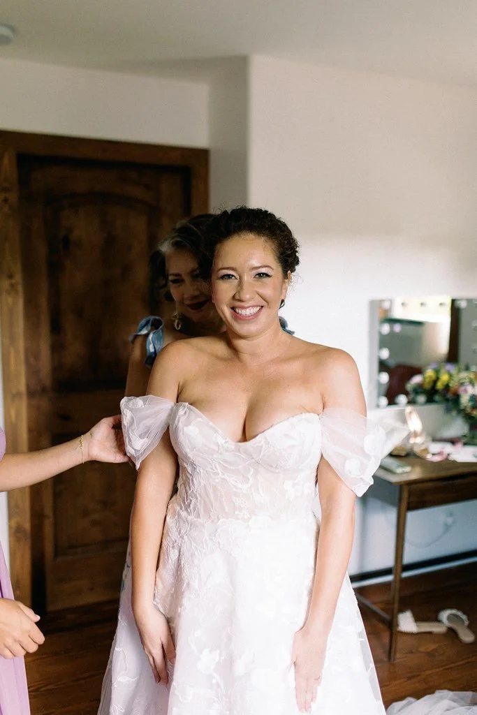 Bridal shop or bedroom with a bride in a white wedding dress, smiling.