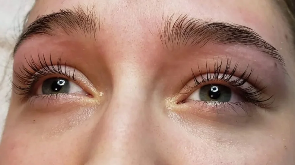 Close-up of a person's eyes, showing long eyelashes, unibrow, and light skin.