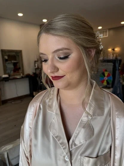 Bride in satin robe with makeup and hair done, preparing for her wedding
