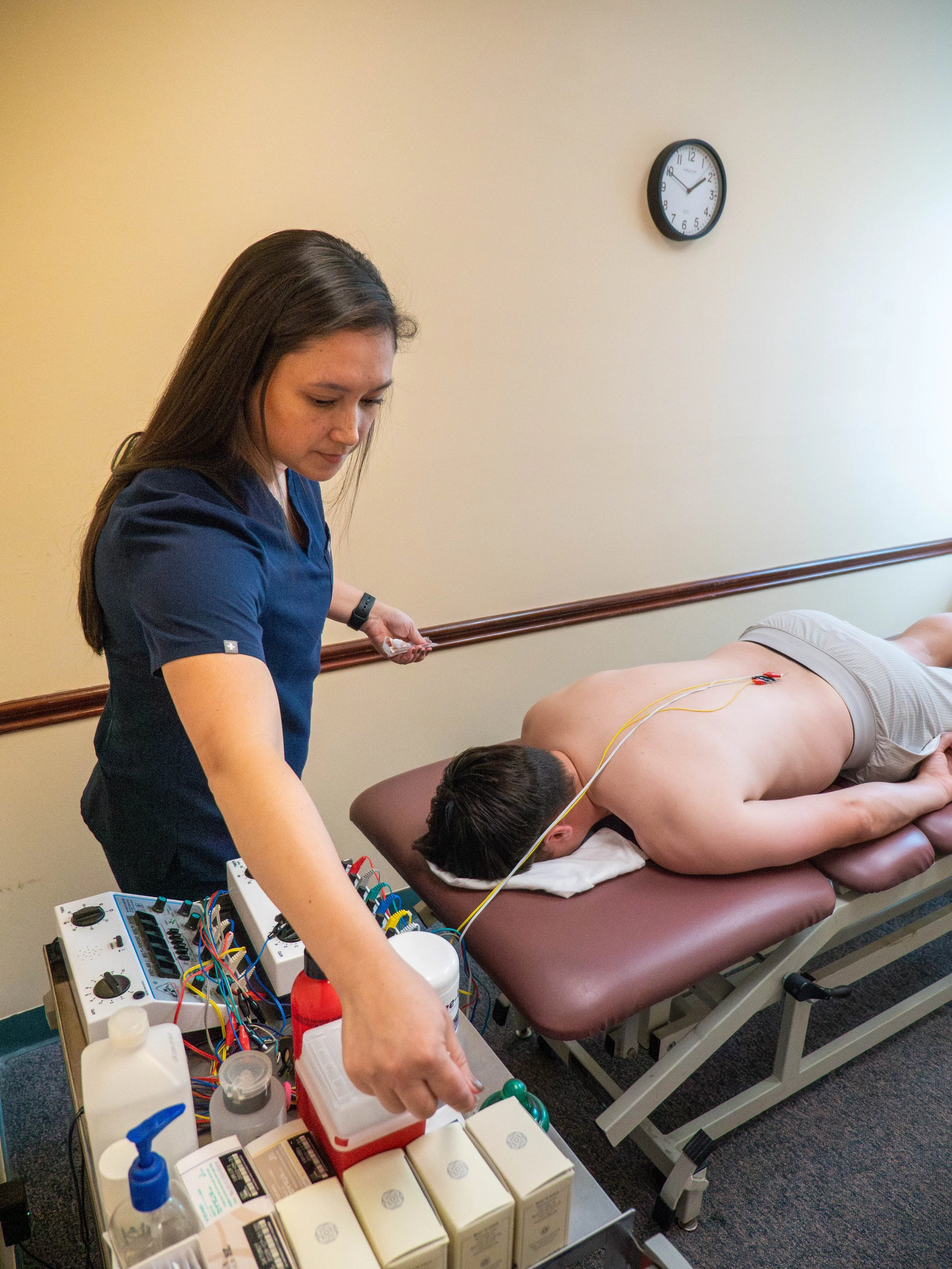 A healthcare professional monitoring a cardiac patient undergoing an electrocardiogram test in a clinical setting.