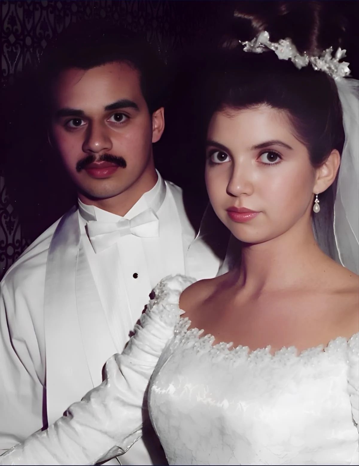 A bride and groom in wedding attire posing for a photo.
