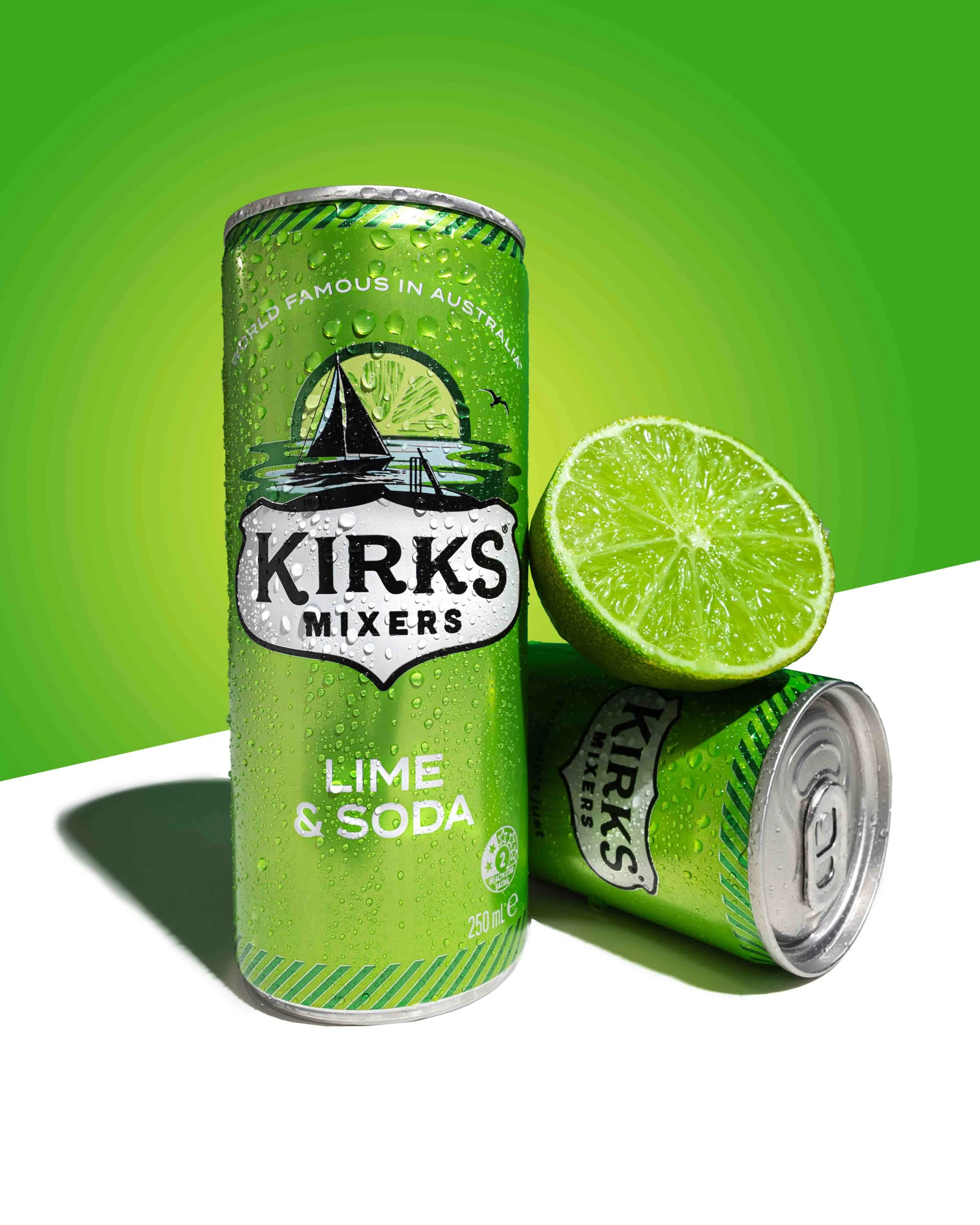 A can of Kirks Mixers Lime & Soda with a halved lime fruit next to it, set against a green background. Photography by Lila Marvell www.lilamarvell.com.au