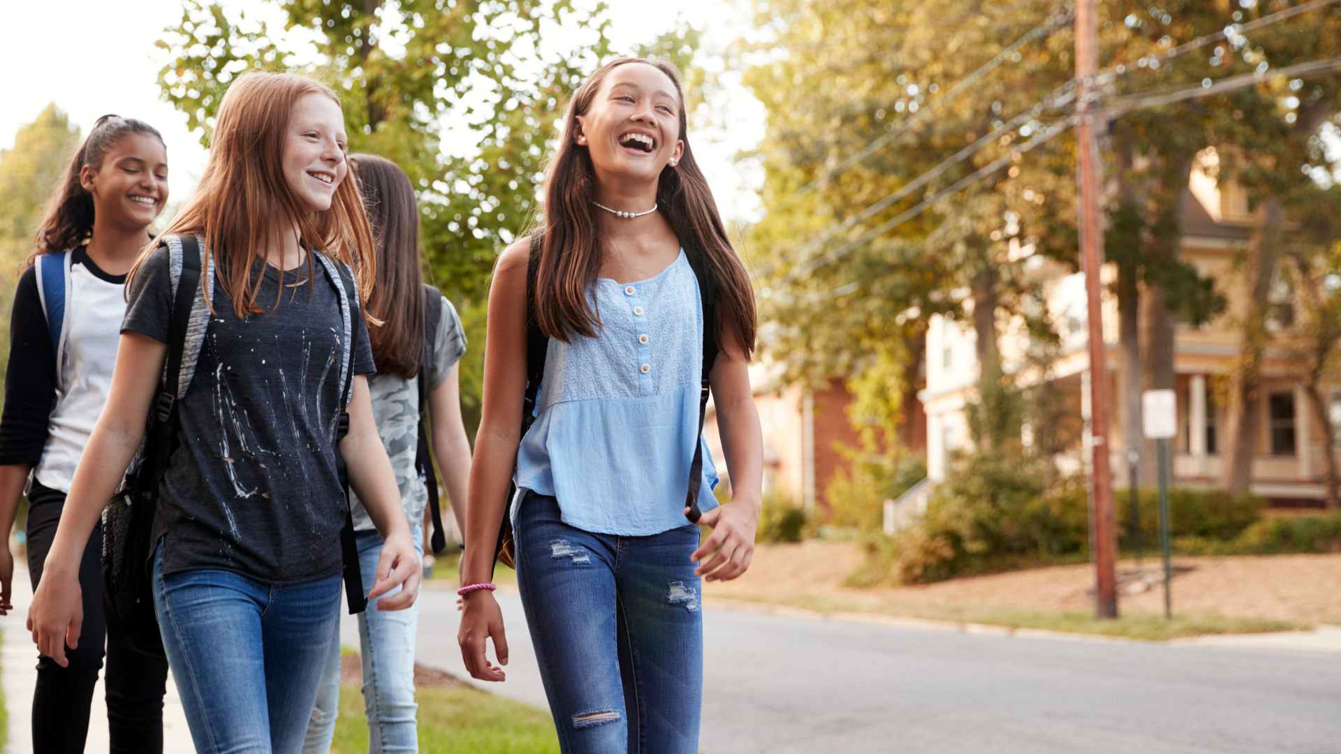 Smiling teen girls walking on a sunny street.