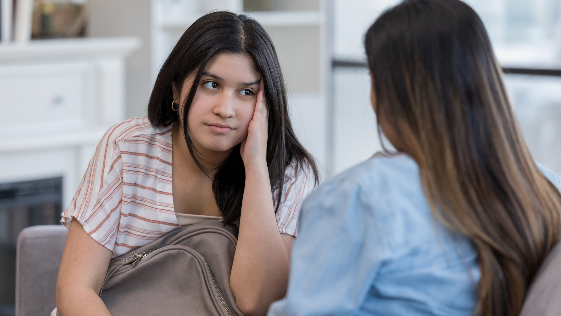 A mother and daughter have a conversation on the couch.