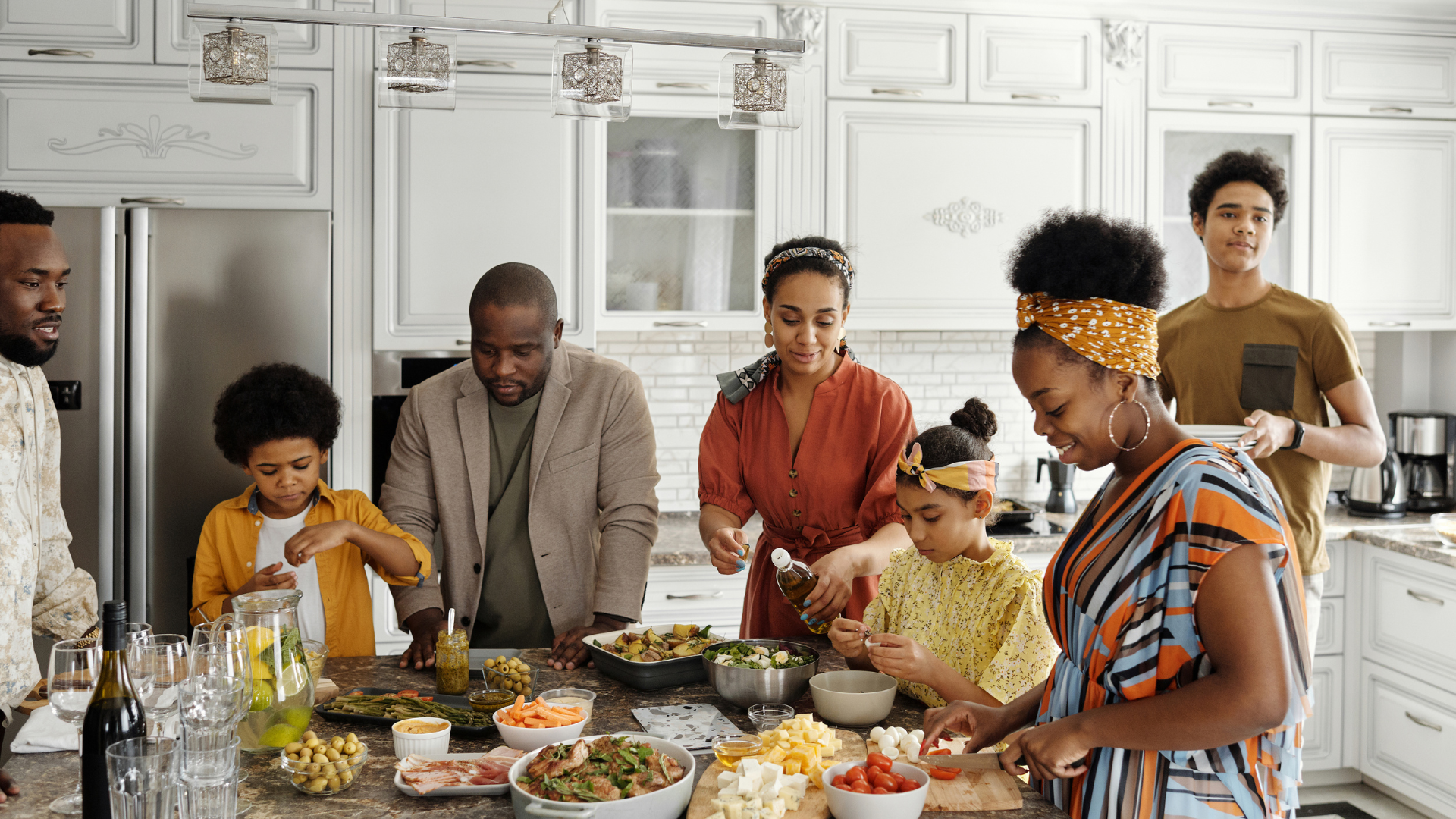 A family gather around a kitchen island preparing a meal together.