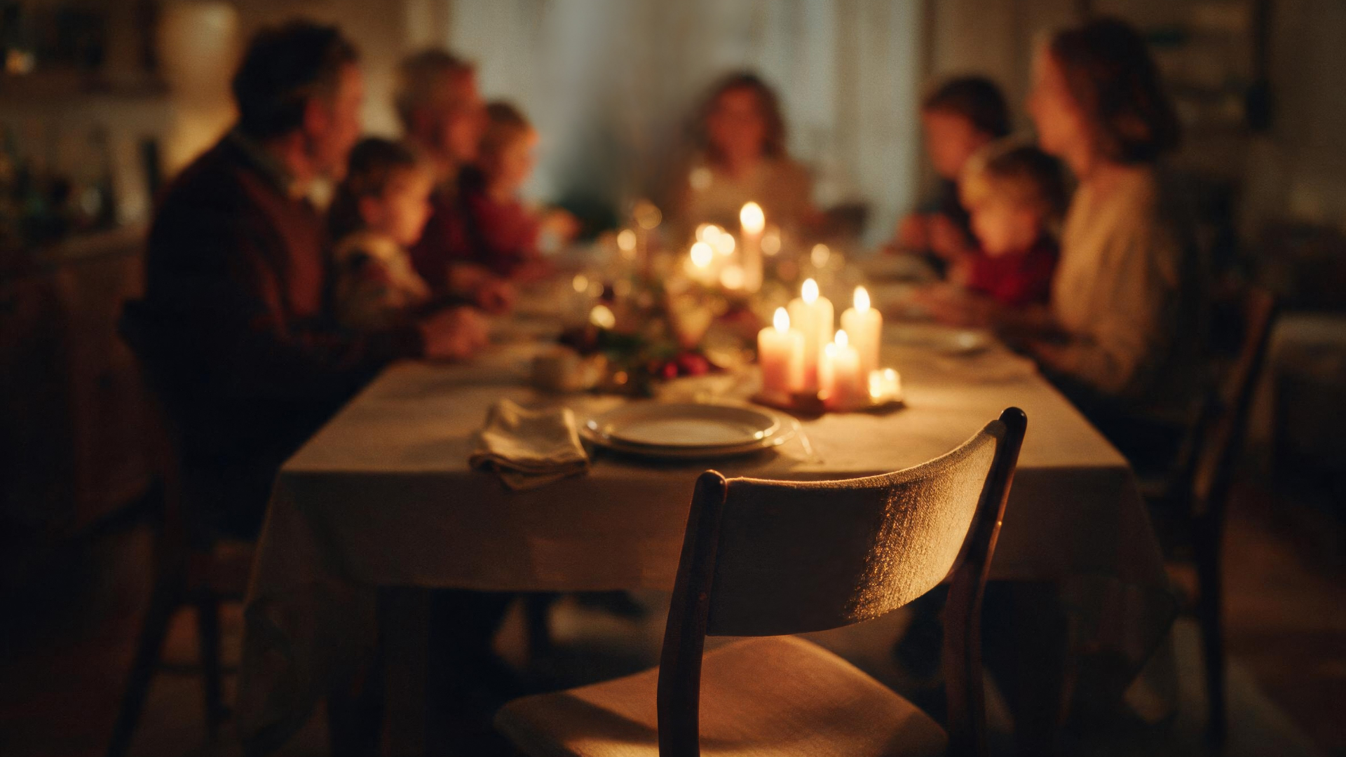 Softly lit image of a family eating dinner at a table.