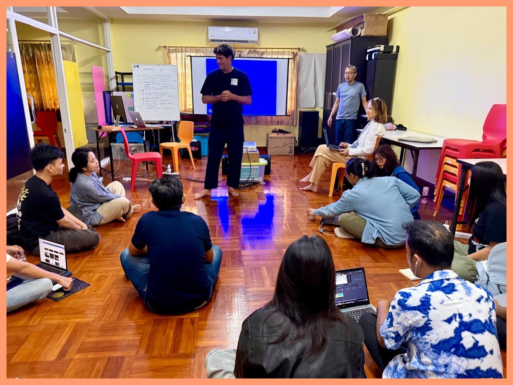 Ken with Students in Burma, they are all seated on the floor looking up at him