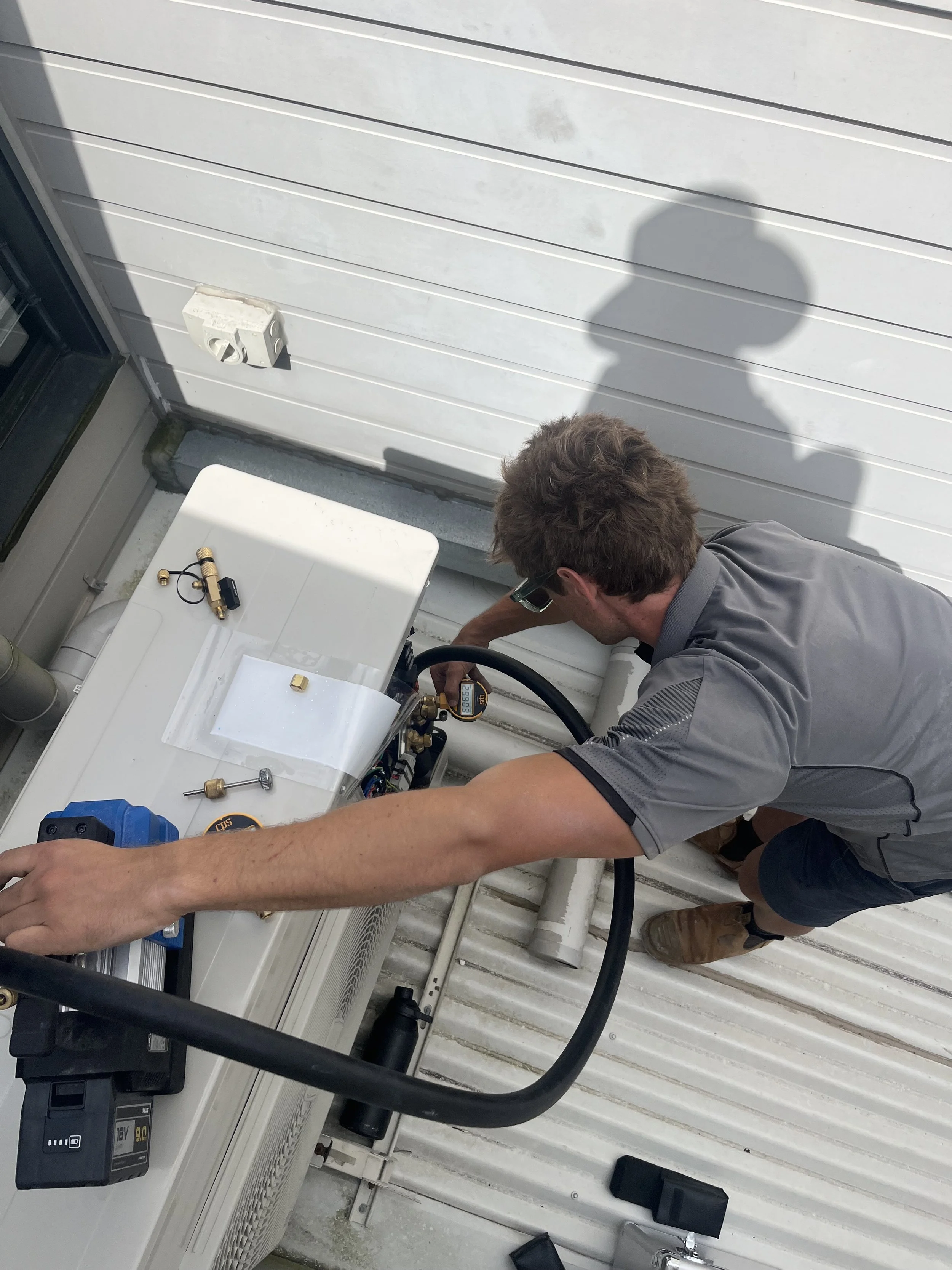 A technician working on an outdoor air conditioning unit or HVAC system.
