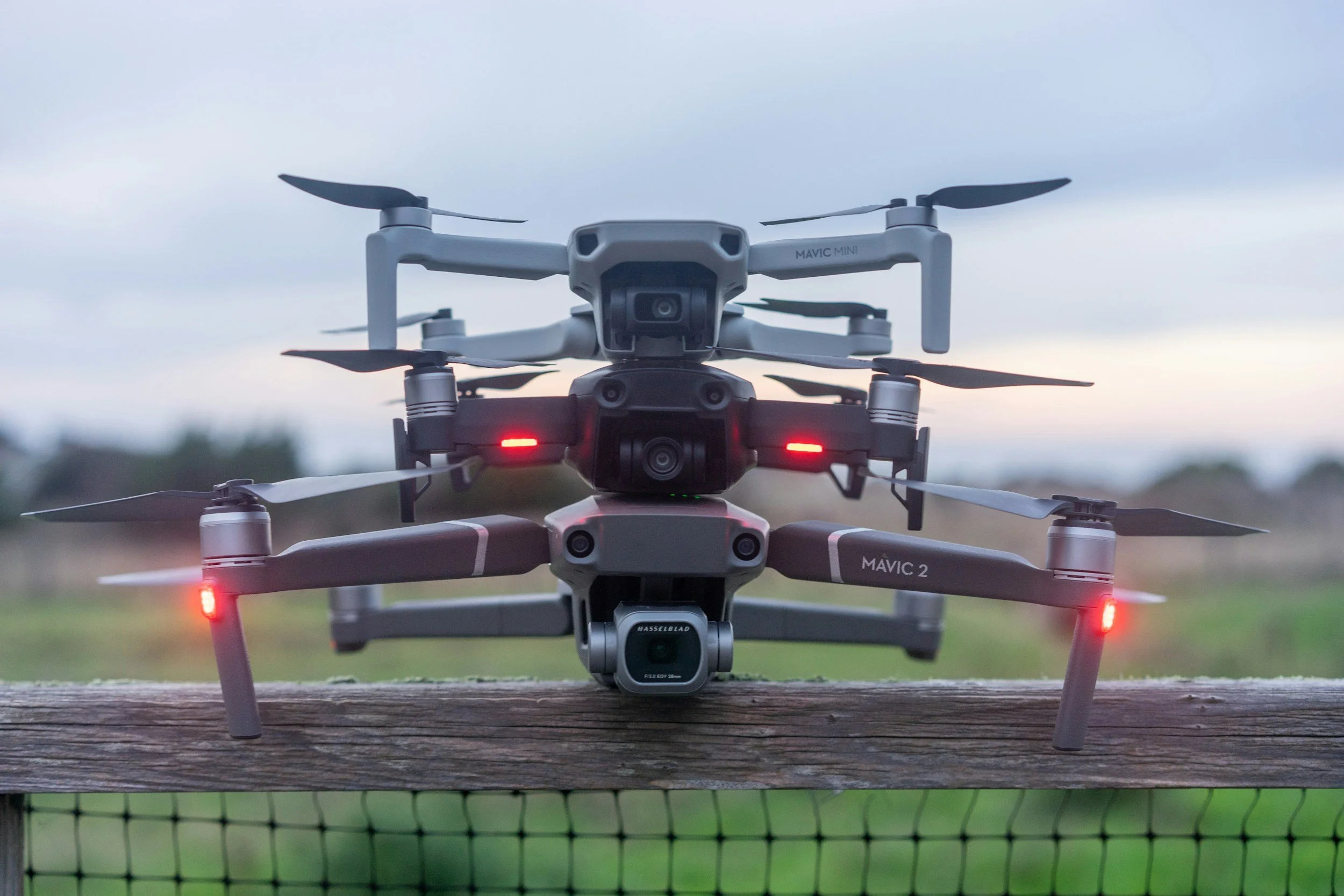 A DJI Mavic 2 drone resting on a wooden surface outdoors with a cloudy sky in the background.
