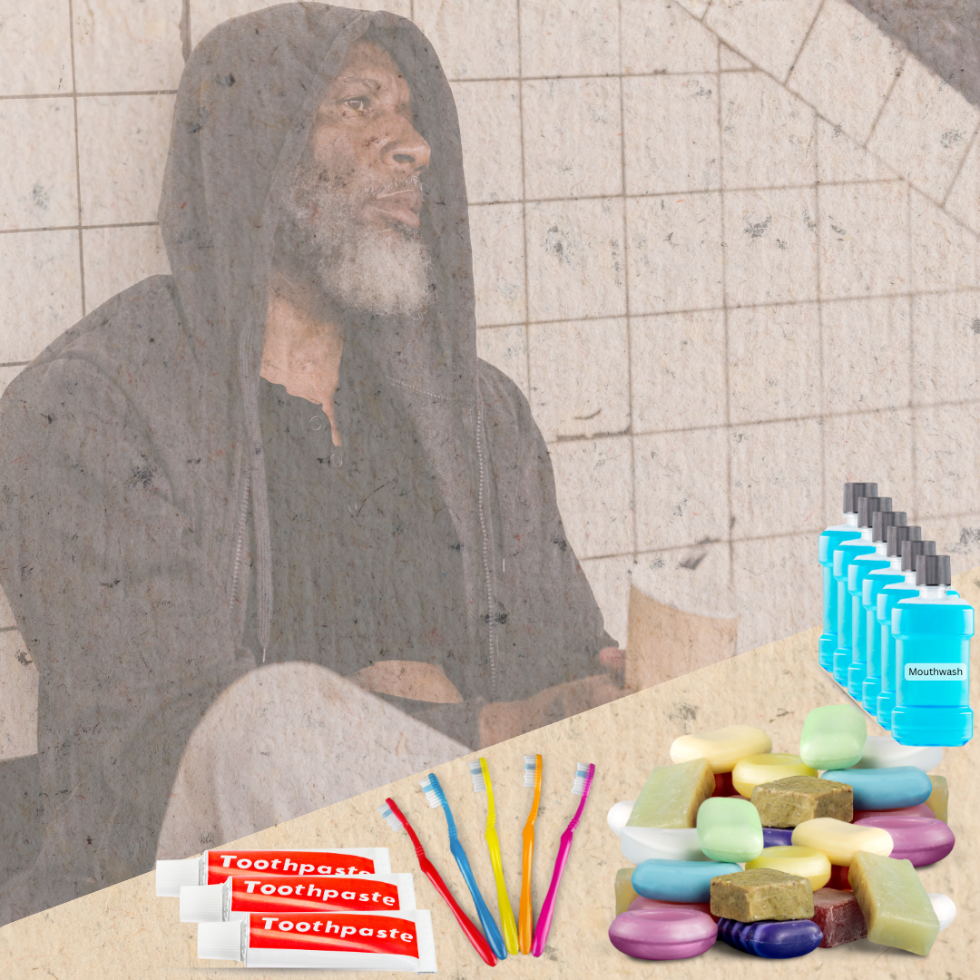 Shows a homeless man sitting against a wall. In front of him is a table with toothpaste, brushes, soap, and mouthwash