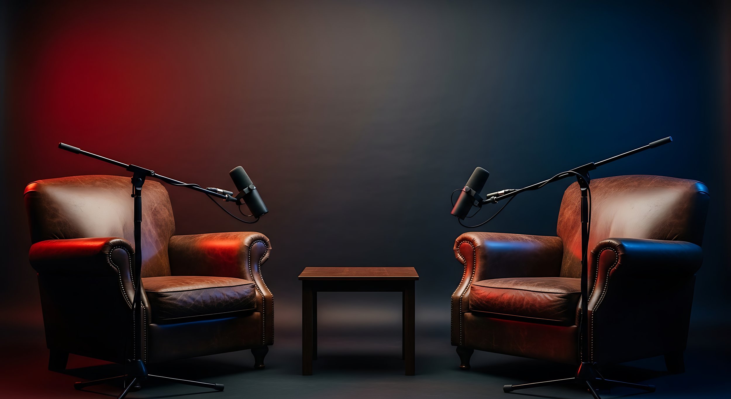 Two leather armchairs facing each other with a small wooden table between them, microphones on stands positioned in front of each chair, set against a dark background with red and blue lighting accents.