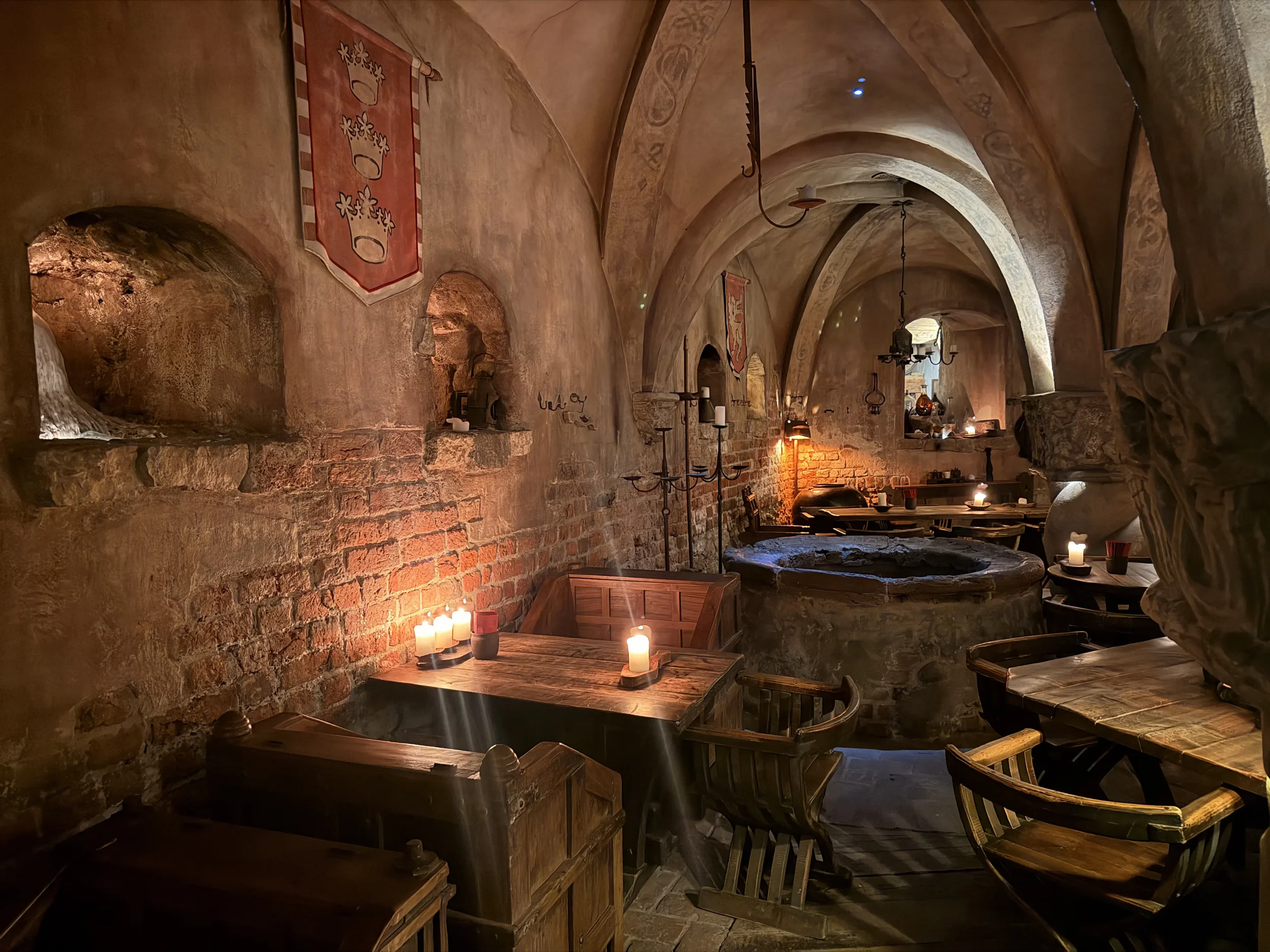 Candlelit medieval cellar restaurant in Riga with stone arches, wooden tables, and warm ambient lighting.