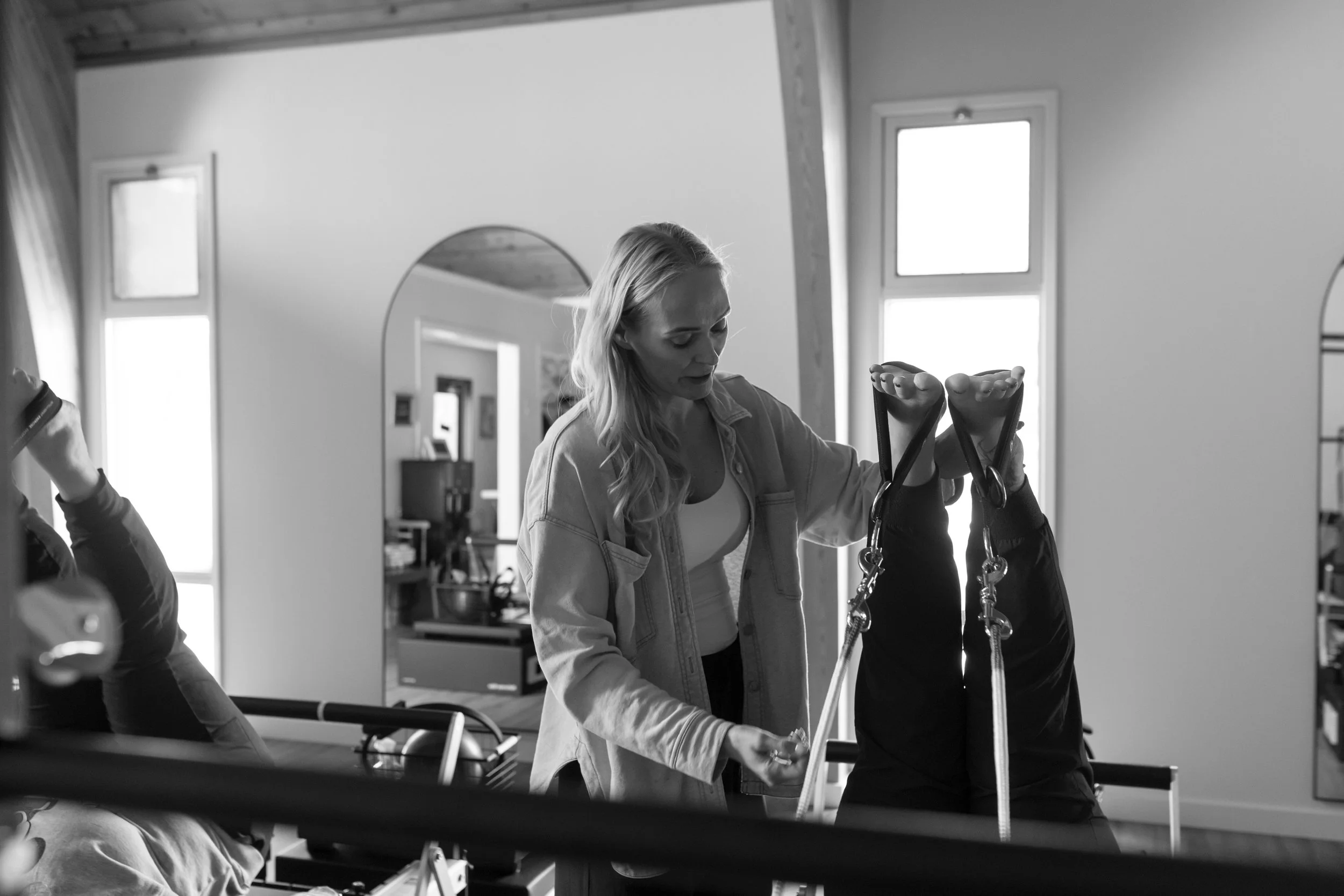 A woman helping a patient exercise with resistance bands in a bright room.