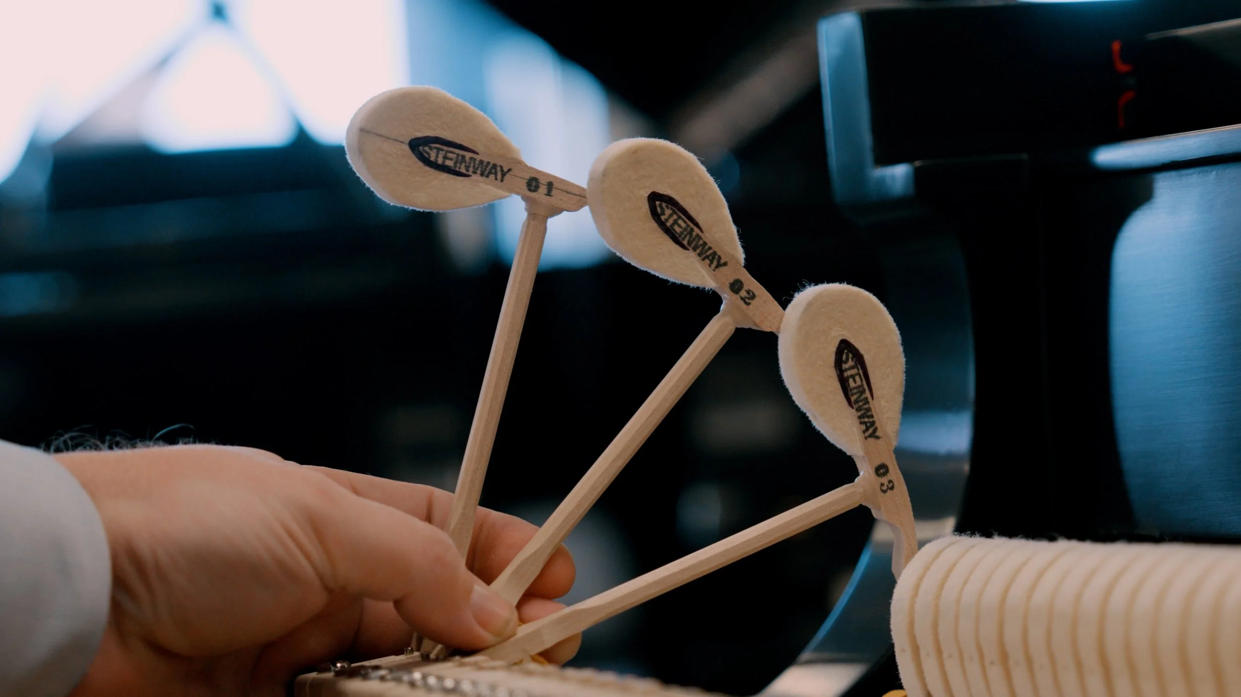 Three wooden golf club covers labeled 01, 02, and 03 being held by a hand near a black golf bag and towel.