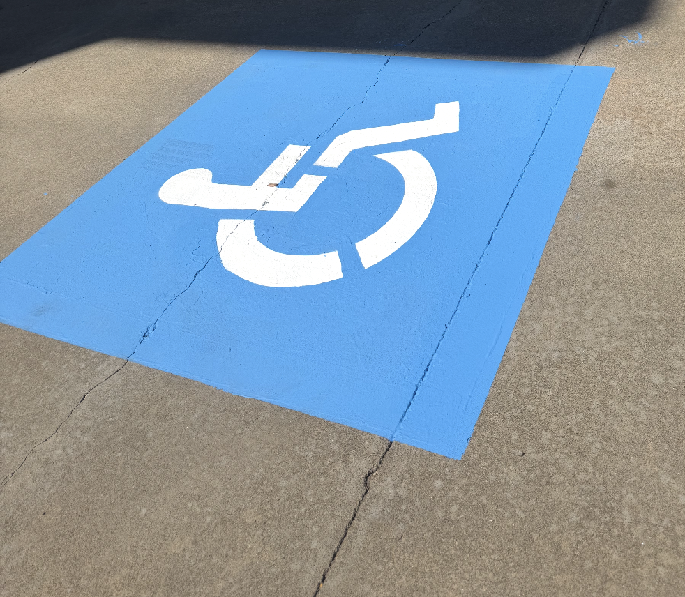 Blue handicapped parking space with a white wheelchair symbol painted on it.