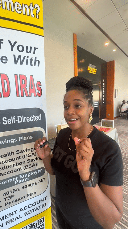 Young woman speaking or presenting near a large informational poster at an indoor event.