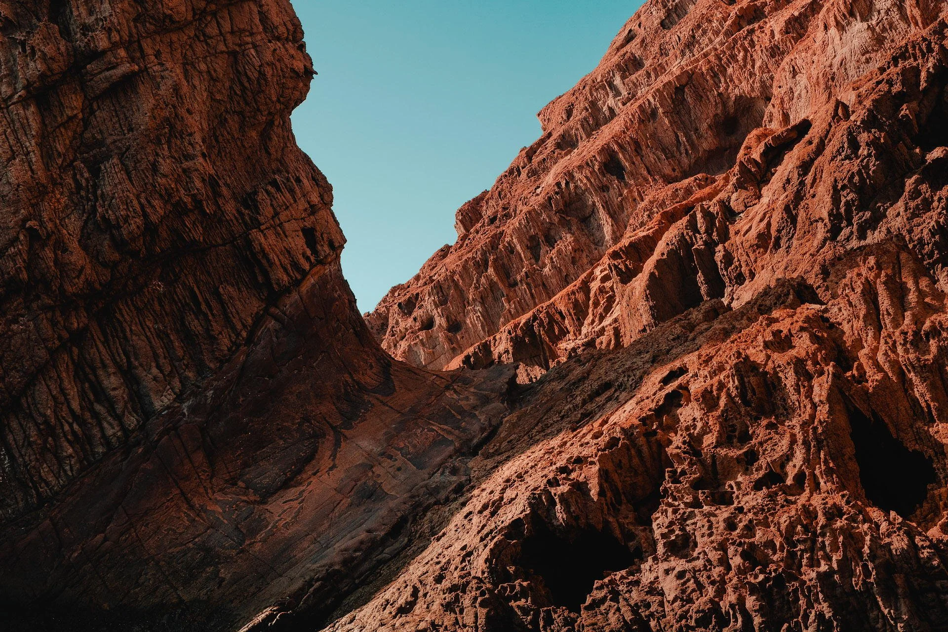 Close-up of rugged red rock canyon walls under a clear blue sky.