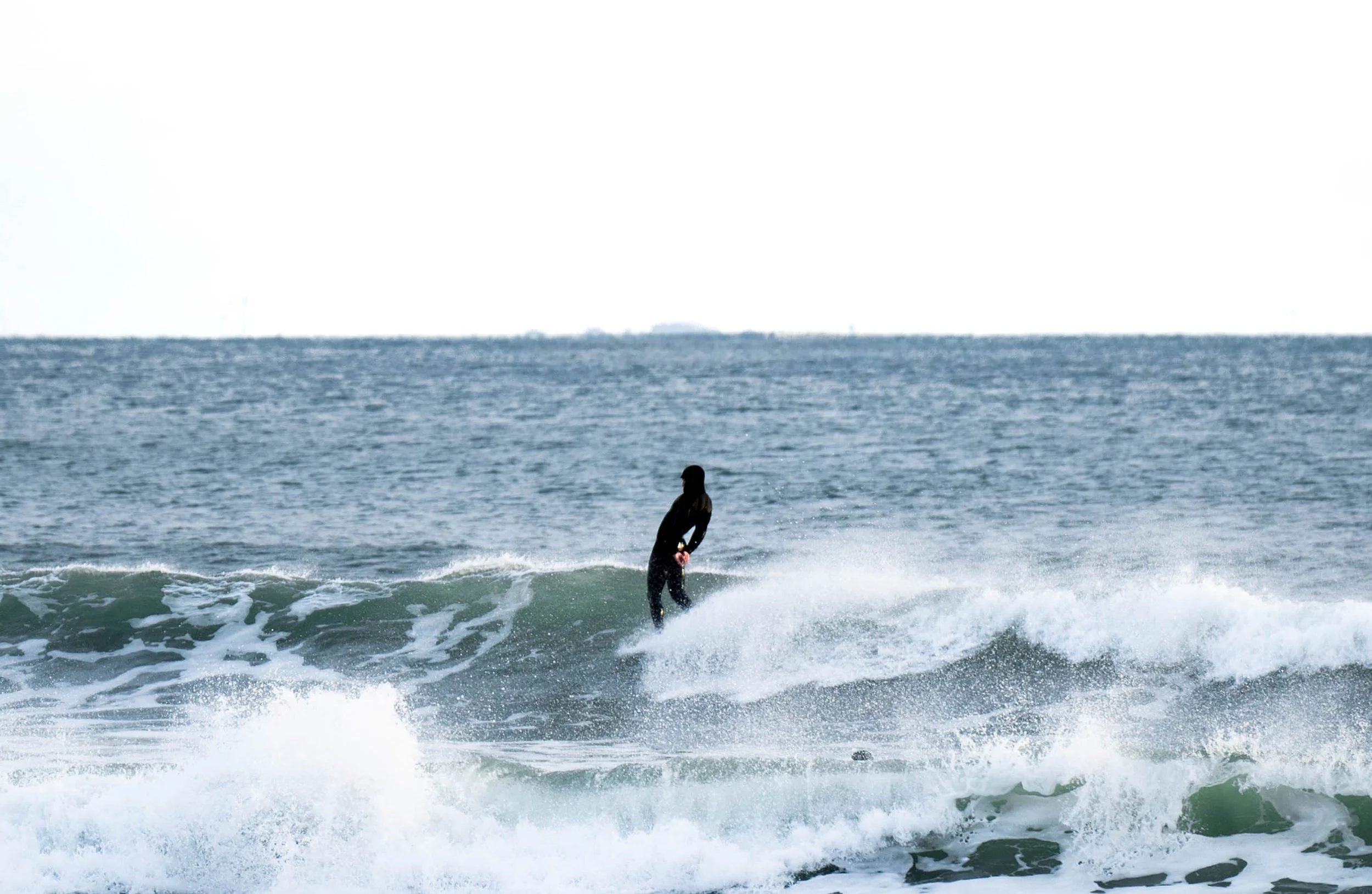 Person surfing on a wave at the beach with the ocean in the background.