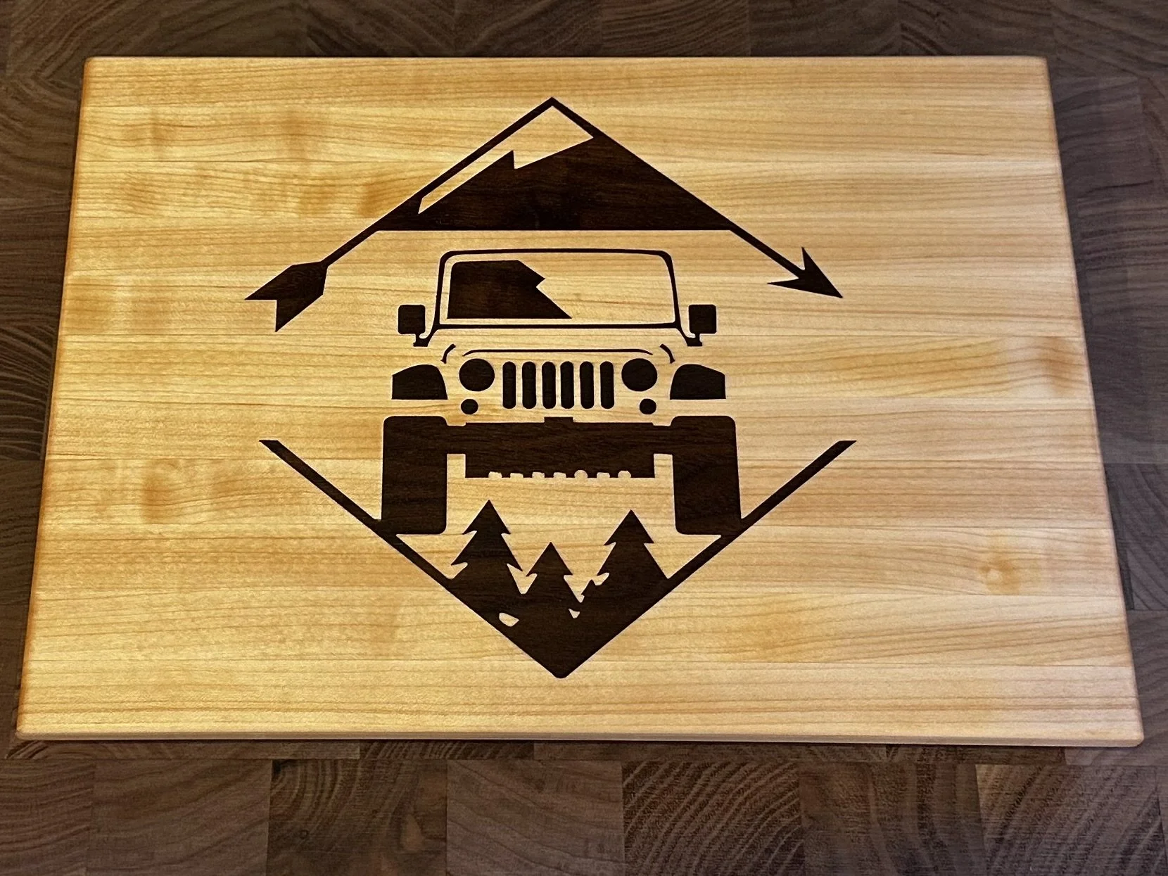 Wooden box with a black graphic of a Jeep vehicle and mountain with arrows, and trees underneath.