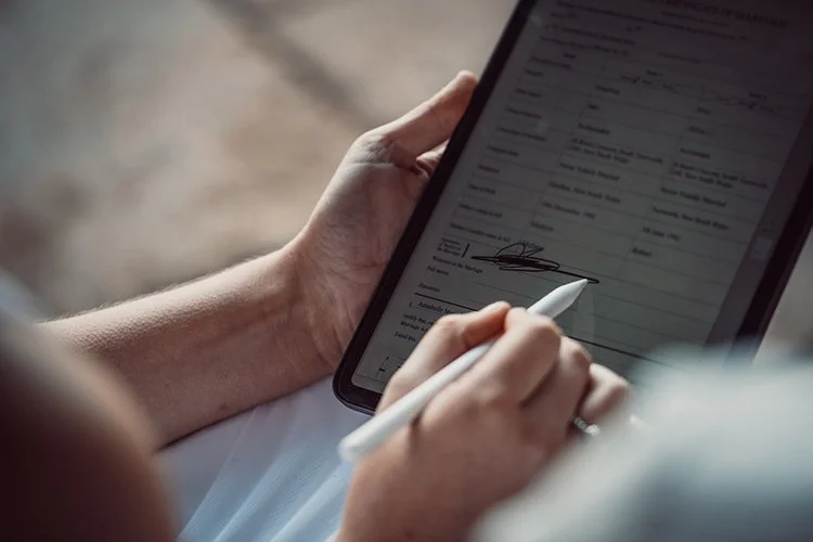 Person signing a document on a tablet with a stylus.