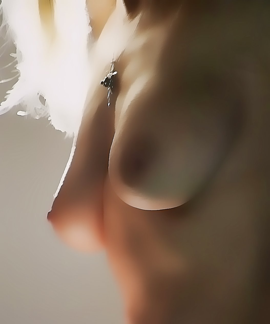 Close-up of a person wearing white feathered accessories and a necklace with a cross pendant, with the focus on their chest and shoulder area.